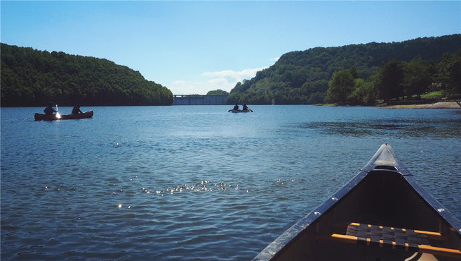 于温暖阳光之下，在满眼绿意的サホロ湖的平稳湖面上划独木舟，度过轻松惬意的时光。