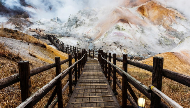 “登别地狱谷”，这是一万年前形成的火山口遗迹，硫磺味弥漫，不时喷出阵阵白烟，举目所见皆寸草不生的岩丘，故得地狱谷之名。