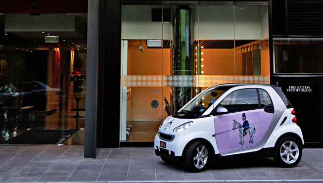 酒店大堂前门，门口停放着装饰有亚当.卡伦作品的Smart轿车。
