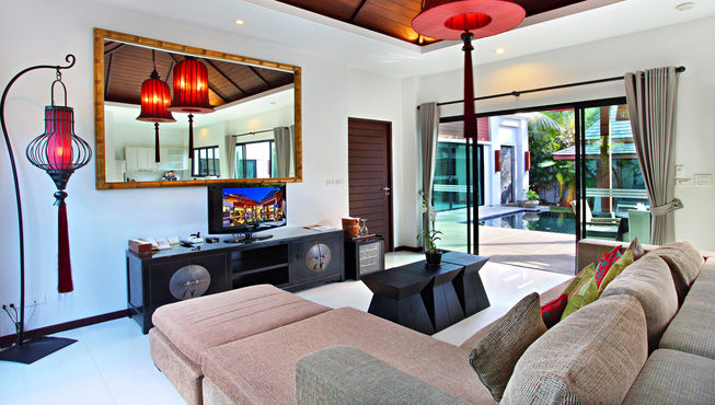 别墅内设施齐全，宽敞的起居室内有舒适的沙发和带有浓郁普吉特色的吊灯。